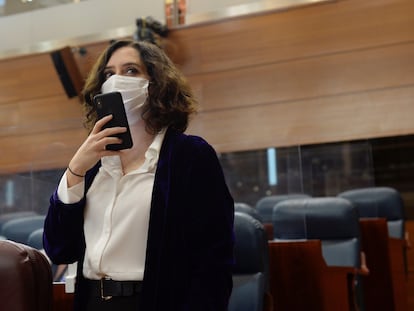 La presidenta de la Comunidad de Madrid, Isabel Díaz Ayuso (d), manda un mensaje con su teléfono a su llegada a la sesión del pleno de la Asamblea del pasado 17 de diciembre.