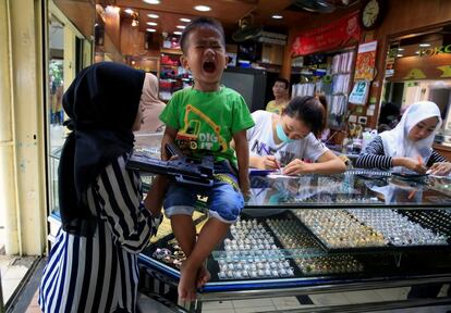 Un niño grita mientras acompaña a su madre a comprar un anillo de oro en una tienda en Yakarta (Indonesia), el 12 de diciembre de 2017.