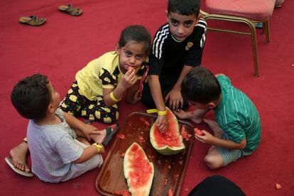 Unos niños comen sandía con las manos en el suelo de la iglesia de Ainkawa.