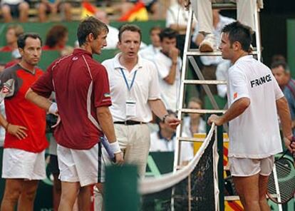 Juan Carlos Ferrero y Fabrice Santoro intercambian impresiones sobre la suspensión de su partido.