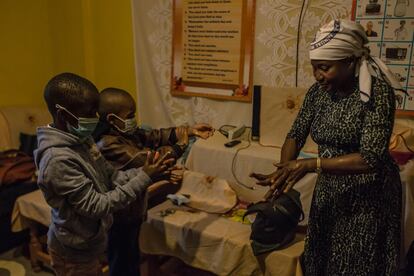 En la imagen, la keniana Betty Muhambe, de 49 años, da desinfectante a su nieto Travis, de siete, y a un amigo de este antes de acudir a misa en el suburbio de Kawangware, en la capital de Nairobi. Las campañas de concienciación sobre el lavado de manos para evitar el contagio por covid-19 han sido muy persistentes en Kenia.
