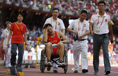 El corredor chino de los 110 metros vallas Zhang Honglin, es retirado en silla de ruedas después de sufrir una caida