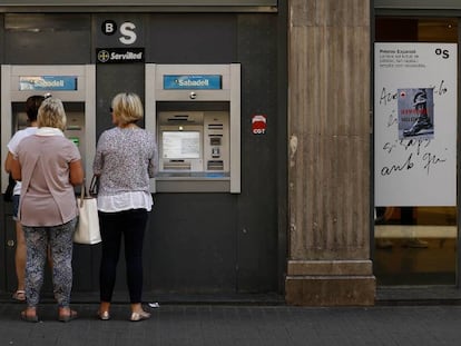 Gente saca dinero en un cajero, en La Rambla de Barcelona.