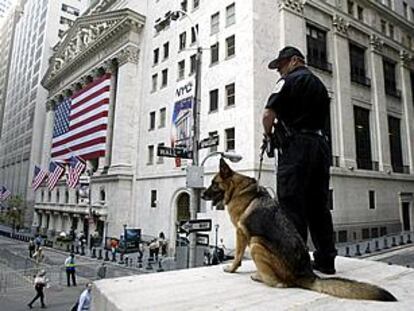 Un policía y un perro adiestrado vigilan la entrada del edificio de la Bolsa de Nueva York, en Wall Street. PLANO GENERAL - PAISAJE URBANO