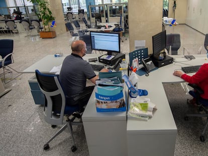 Dos empleados, en su puesto de trabajo de una oficina de Hacienda en Madrid, en julio de 2021.