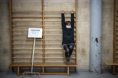 Una apoderada de una mesa hacía estiramientos en las espalderas del gimnasio del colegio donde estaban algunas de las mesas para las votaciones, en un colegio de Valladolid.