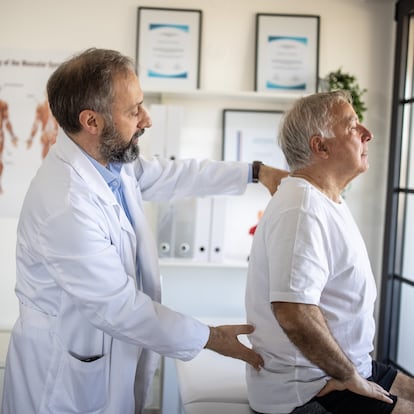 Physical therapist examining senior patient's back injury at doctor's office