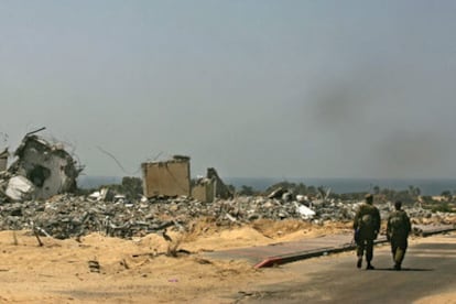 Dos militares israelíes pasan junto a una de las viviendas demolidas del asentamiento de Rafiah Yam, en la franja de Gaza.