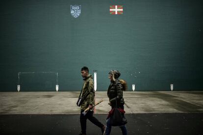 Dos personas caminan delante de una pared con la bandera vasca, en Hernani.