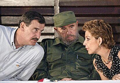 El presidente de México, Vicente Fox, habla con su esposa en presencia del presidente cubano, Fidel Castro.
