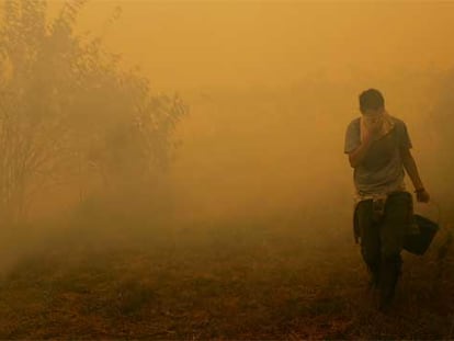 El humo obliga a un vecino de Cotobade (Pontevedra) a protegerse la cara con un pañuelo.