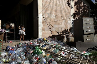 Una niña indígena en la comunidad de Cerro Poty junto a un montón de botellas para reciclar y a los archivadores de la escuela que se inundó hace meses y continúa inutilizada.