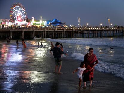 Personas juegan en las olas junto al muelle de Santa Mónica, en Los Ángeles (California).
