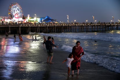 Personas juegan en las olas junto al muelle de Santa Mónica, en Los Ángeles (California).