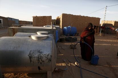 Una mujer saharaui llena un recipiente con agua de una cisterna fuera de su tienda en el campo de refugiados de Smara en Tinduf.