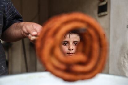 Un vendedor prepara 'zalabiya', un dulce, bajo la atenta mirada de un niño en Alepo (Siria).