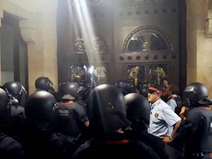 Mossos tancats al Parlament, mentre els manifestants donen cops a la porta.