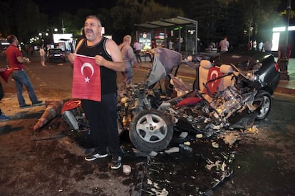 Un hombre posa junto a un coche destruido por un tanque en la plaza Kizilay (Ankara) donde la gente se reúne para protestar en contra del golpe militar, el 16 de julio de 2016.