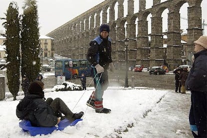 Varias personas disfrutan de la nieve junto al acueducto de Segovia