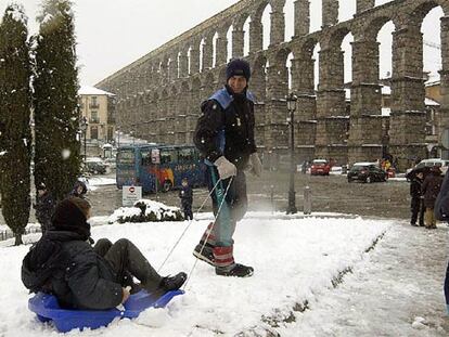 Varias personas disfrutan de la nieve junto al acueducto de Segovia