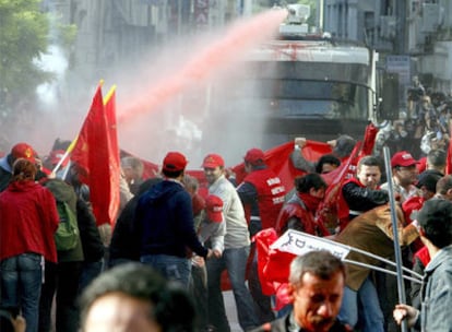 Un grupo de manifestantes se resguardan del chorro de agua a presión disparado desde una tanqueta de la policía, en la manifestación del Primero de Mayo en Estambul.
