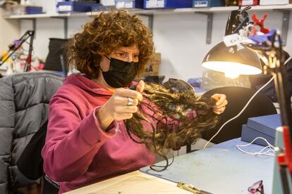 Una artesana trabaja con mechones de pelo natural para elaborar una peluca.