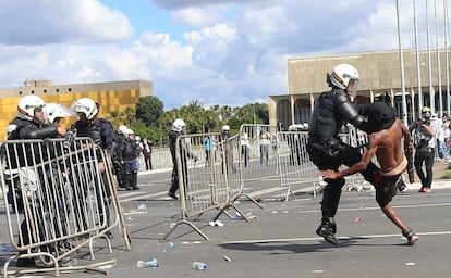 Un manifestante y un antidisturbio se enfrentan durante las protestas de Brasilia.