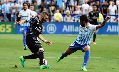 El delantero francés del Real Madrid Karim Benzema regatea al jugador del Málaga, Miguel Torres, durante una acción del partido.