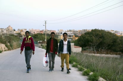 Tres inmigrantes rescatados la semana pasada y conducidos a Lampedusa se dirigen al centro de acogida de la isla.