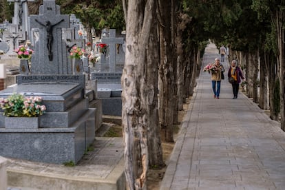 Dos mujeres conversan mientras se dirigen a dejar flores en la tumba de algún ser querido en el cementerio de Toledo.