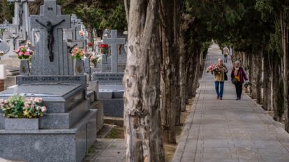 Dos mujeres conversan mientras se dirigen a dejar flores en la tumba de algún ser querido en el cementerio de Toledo.