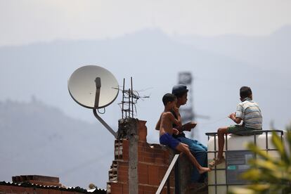 Unos niños juegan en un tejado junto a una antena de televisión por cable en el barrio caraqueño de Catia, este martes.