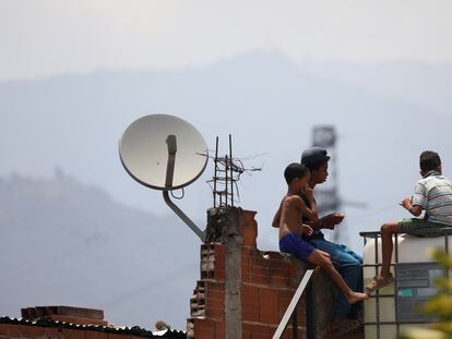 Unos niños juegan en un tejado junto a una antena de televisión por cable en el barrio caraqueño de Catia, este martes.