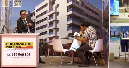 Un pareja se interesa por una promoción en una feria inmobiliaria.