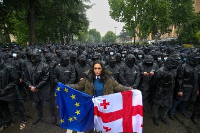 Una mujer sujetaba las banderas de Georgia y de la UE en una calle de Tbilisi delante de un grupo de antidisturbios durante las protestas del pasado mayo por la aprobación de la ley de agentes extranjeros.