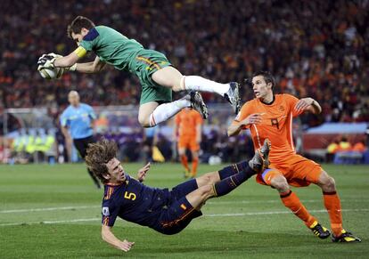 El portero español, Iker Casillas vuela tras atrapar el balón después de un choque con Puyol ( abajo) , ante el jugador holandés Van Persie ,en el partido de la final de la Copa del Mundo de Sudáfrica 2010, donde España gano a Holanda por 1- 0, a cuatro minutos del final de la prórroga, en el estadio Soccer City, en Johanesburgo.