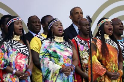 Barack Obama junto al presidente sudafricano, Cyril Ramaphosa, detrás de los miembros del coro de Gospel de Soweto cantando el himno nacional de Sudáfrica.