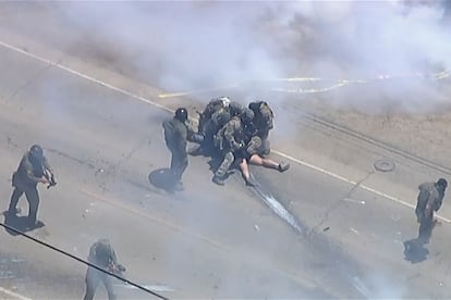 Agentes federales detienen a un manifestante mientras lanzan gases lacrimógenos durante una redada de inmigración en una instalación agrícola al sur de California.