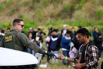 Un agente fronterizo ofrece una botella de agua a un migrante en la frontera de Estados Unidos con México, cerca de Tijuana, este lunes. 