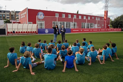 El ex jugador Adelardo y la psicóloga Isabel Gutiérrez repasan conceptos sobre el acoso mientras un grupo de jóvenes de la Fundación Atlético de Madrid posan para una foto en un campo de la Ciudad Deportiva del Atlético de Madrid en Majadahonda, Madrid.