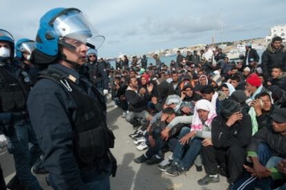 Policías italianos junto a un grupo de emigrantes norteafricanos antes de que embarquen con destino a otros centros de acogida temporal en Italia.