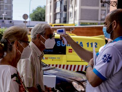 Un trabajador sanitario toma la temperatura a un hombre protegido con mascarilla este miércoles en Madrid.