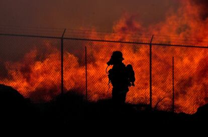 Un bombero pasa junto a un muro de fuego en un centro de reciclaje en Riverside (California).