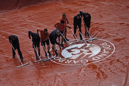 Los operarios secan la cubierta de la cancha durante una parón de la semifinal.