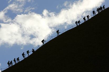 Turistas escalando la cima del Uluru.