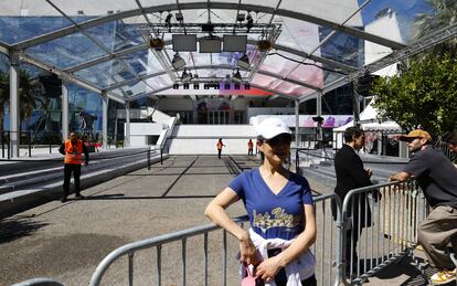 Una turista posa este lunes ante la puerta principal del Palacio de festivales, donde falta por desplegar la alfombra roja.