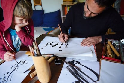 Ali writes calligraphy under the watchful eye of his son.