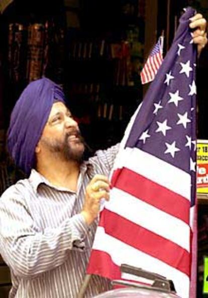 Un inmigrante sij de India coloca una bandera en su tienda de Manhattan.