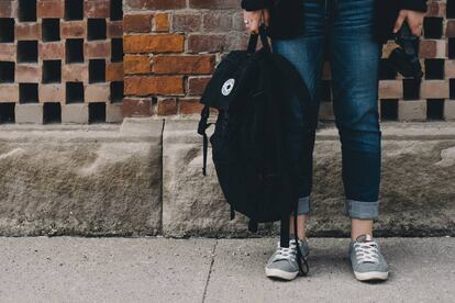 Una adolescente sujeta su mochila para ir a clase.