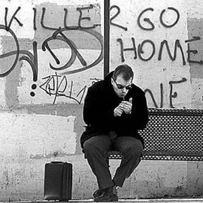 Un ciudadano de Atenas enciende un cigarrillo en una parada de autobús del centro de la ciudad.